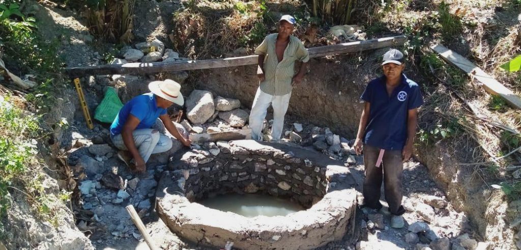 three men constructing a well
